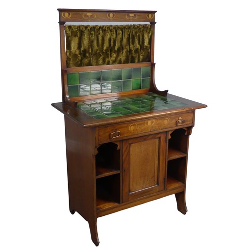 An unusual small Arts and Crafts mahogany Dresser / Washstand, with green tiles and stylised floral inlay to top and drawer, gold green curtain to back, W 77 cm x H 131 cm x D 50 cm. Provenance: property of a West Country Collector. After buying an Arts & Crafts house, the vendors researched and sought-out beautiful, often unique, Arts & Crafts pieces to furnish their home.