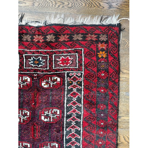 518 - Tribal Rugs; an Afghan red-ground rug, 100% wool, 153cm x 89cm.