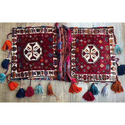 519 - Tribal Rugs; a large Baluchi tent bag/camel bag, 146cm x 80cm, together with a large rug-backed cush... 