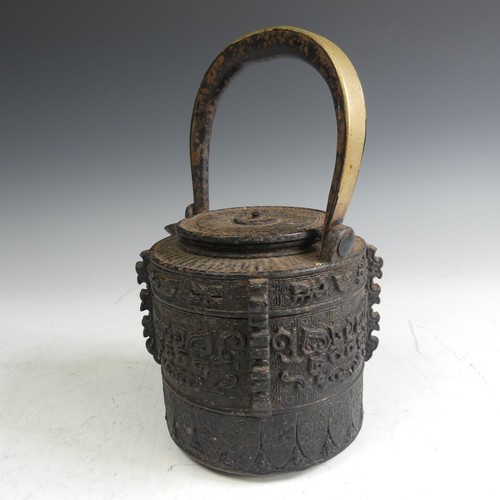 86 - A Japanese cast iron Tetsubin, of cylindrical form with relief work patterns, with swing handle with... 