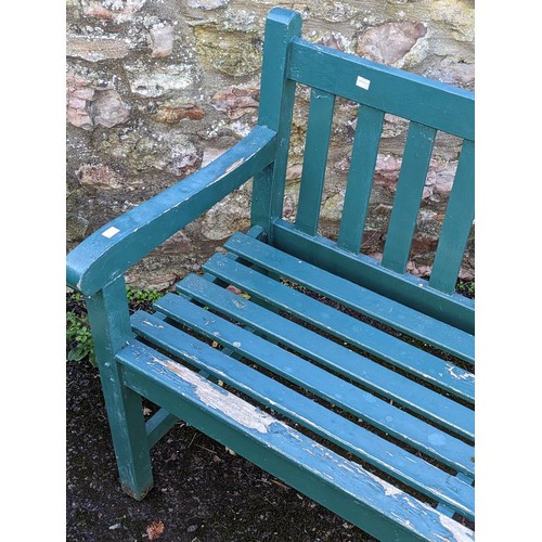 527 - A weathered green painted wooden garden Bench, W 122 cm x H 84 cm x D 57 cm.