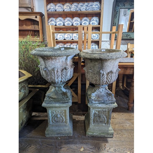 530 - A Pair of weathered reconstituted stone garden Urns of campana form, raised on Art Nouveau inspired ... 