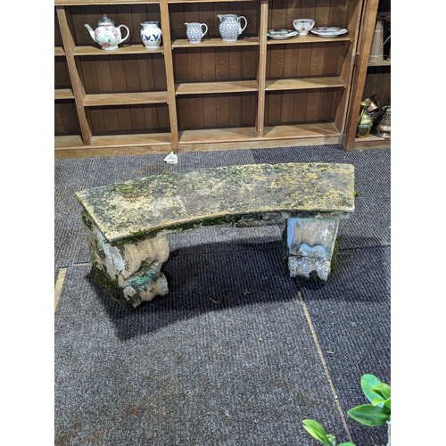 535 - A weathered reconstituted stone curved Garden Seat, on two large carved feet, W 118 cm x H 43 cm x D... 