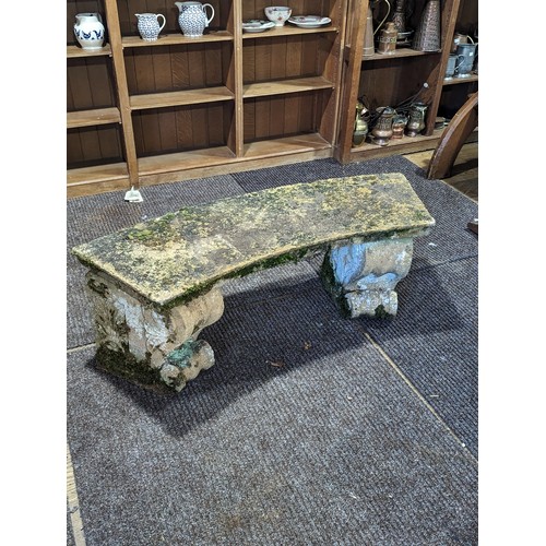 535 - A weathered reconstituted stone curved Garden Seat, on two large carved feet, W 118 cm x H 43 cm x D... 