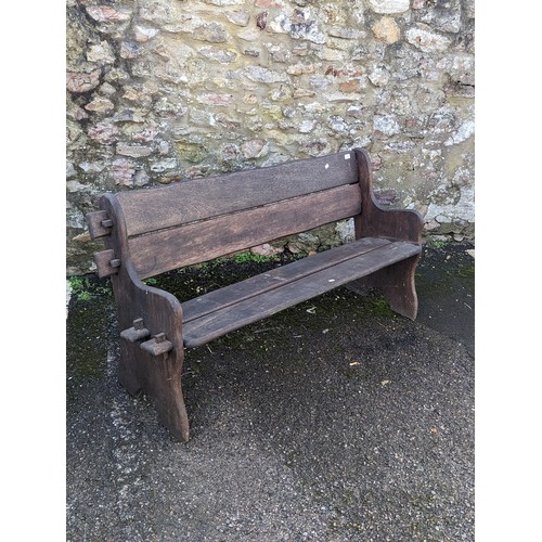 525 - A weathered West African iroko wood two seat garden Bench, with shaped ends and pegged frame, applie... 