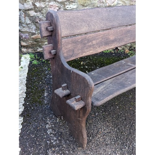 525 - A weathered West African iroko wood two seat garden Bench, with shaped ends and pegged frame, applie... 