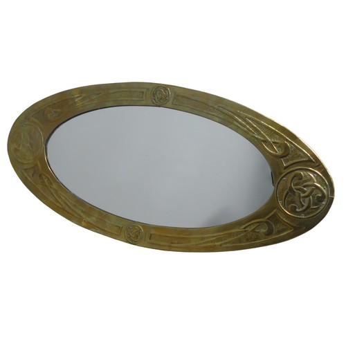 387 - A Glasgow School Arts and Crafts celtic revival brass Mirror, the oval frame repoussé-decorated with... 