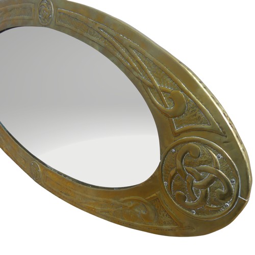 387 - A Glasgow School Arts and Crafts celtic revival brass Mirror, the oval frame repoussé-decorated with... 