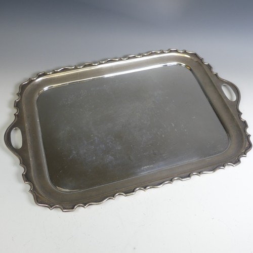 120 - A George V rectangular silver two handled Tray, with plain centre, the shaped rim with cut out oval ... 