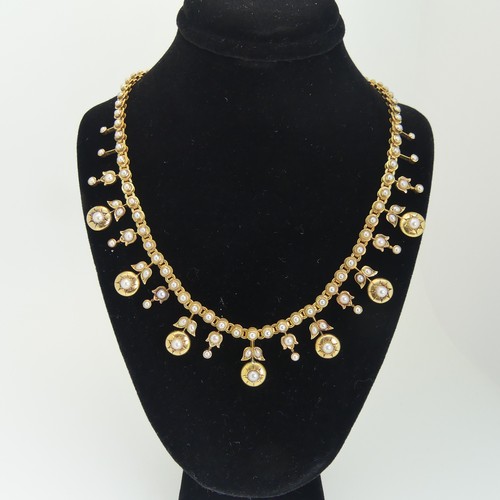 An Edwardian half pearl fringe Necklace, the front with seven circular drops, each gypsy set with a half pearl and with smaller half pearl set drops between, all on an integral half pearl set chain with concealed box clasp, 37cm long, unmarked but tested as 15ct gold, approx. total weight 33.5g.