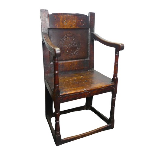 A Charles II Wainscot Chair of joint construction, the top rail carved '1670' above simple carved panel back, swept arms supported on turned and blocked legs, united by solid plain rectangular stretchers, W 53 cm x H 101 cm x D 46 cm.