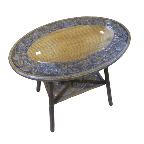 364 - An Arts and Crafts oak carved oval occasional Table, bevelled top with carved stylised floral rim, a... 