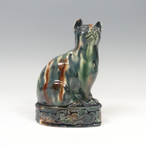 A late 18thC Whieldon- style creamware model of a Cat, in seated position upon plinth with moulded ornate relief, the whole piece generously washed in blues, creams and manganese, H 15cm x L 10cm.