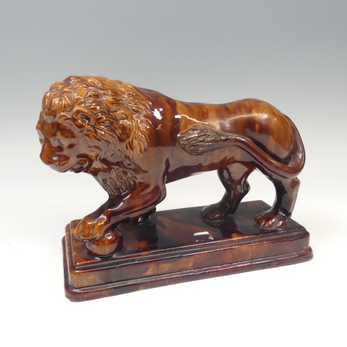 158 - A 19thC treacleware Medici lion Figure, resting its paw on a ball, raised on stepped plinth base, H ... 