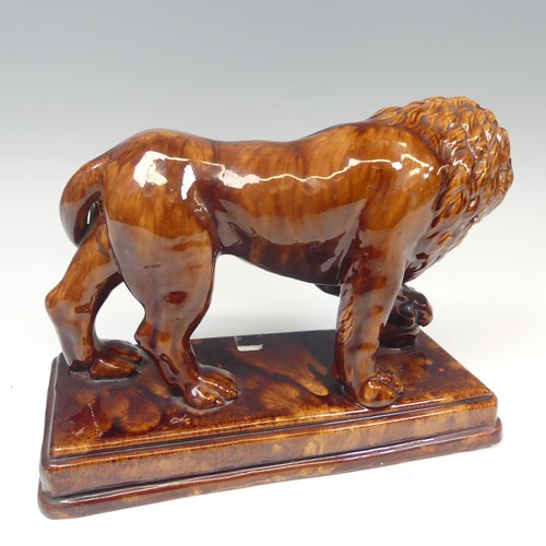 158 - A 19thC treacleware Medici lion Figure, resting its paw on a ball, raised on stepped plinth base, H ... 