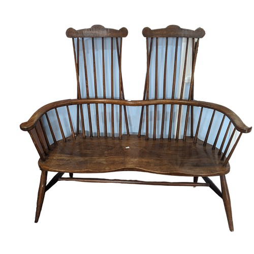 A double Windsor comb back Settle / Bench, comb stick back above shaped seats, raised on four turned legs, W 127 cm x H 119.5 cm x D 45 cm.