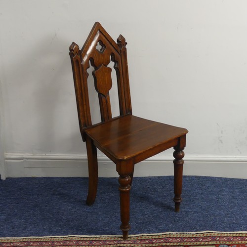 370 - A Victorian oak gothic style hall Chair, with pierced back raised on turned front legs and splayed r... 