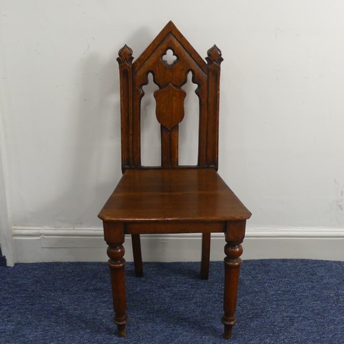 370 - A Victorian oak gothic style hall Chair, with pierced back raised on turned front legs and splayed r... 