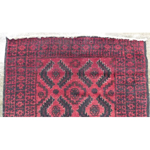 640 - Tribal Rugs; a red ground Afghan rug, wool pile on cotton base, 179cm x 94.5cm, good overall conditi... 