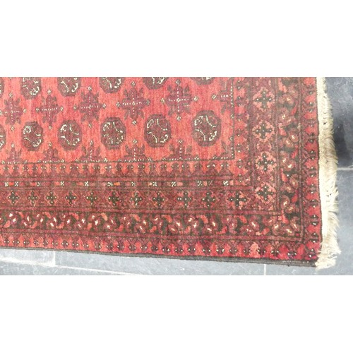 651 - Tribal Rugs; a red ground Afghan runner, wool pile on wool base, 272cm x 82cm, pile worn in places.... 