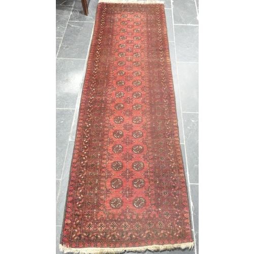 651 - Tribal Rugs; a red ground Afghan runner, wool pile on wool base, 272cm x 82cm, pile worn in places.... 