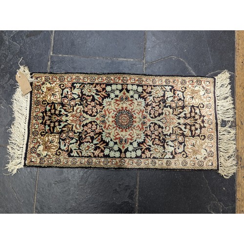 638 - Tribal Rugs; a small silk Kashmiri Mat, 72cm x 30cm, together with two other small rugs, one with ev... 