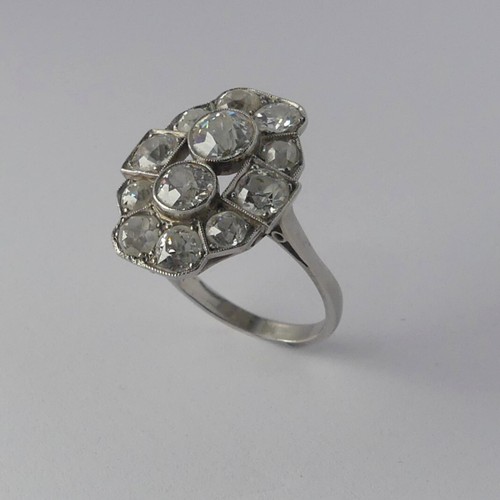 282 - An Art Deco diamond Cluster Ring, the old cut stones millegrain set in platinum on a plain shank, th... 