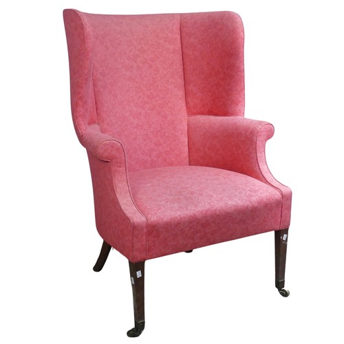 510 - An antique wing-back Armchair, upholstered in pink, raised on tapering front legs with castors and r... 