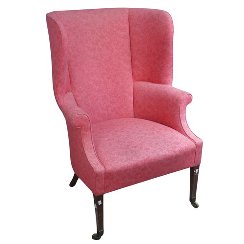 510 - An antique wing-back Armchair, upholstered in pink, raised on tapering front legs with castors and r... 