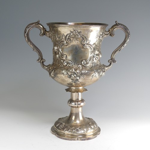 A Victorian silver two handled Trophy Cup, by Daniel & Charles Houle, hallmarked London, 1867, of goblet form with repoussé foliate decoration, correspondingly decorated shaped circular foot with a knopped stem, leaf capped scroll handles, one side with later presentation inscription, the other cartouche blank, 32cm high, approx. total weight 43.1ozt.