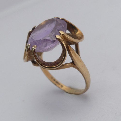 249 - An amethyst Dress Ring, the pale oval facetted stone approx. 14mm long, in scrolling 9ct gold mount,... 