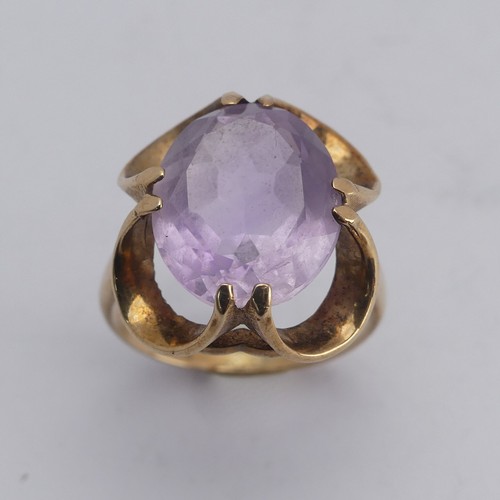 249 - An amethyst Dress Ring, the pale oval facetted stone approx. 14mm long, in scrolling 9ct gold mount,... 