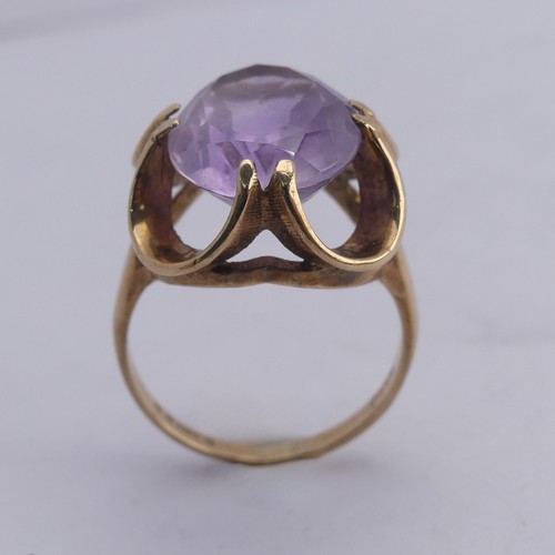 249 - An amethyst Dress Ring, the pale oval facetted stone approx. 14mm long, in scrolling 9ct gold mount,... 