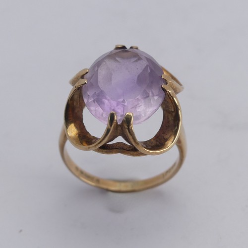 249 - An amethyst Dress Ring, the pale oval facetted stone approx. 14mm long, in scrolling 9ct gold mount,... 