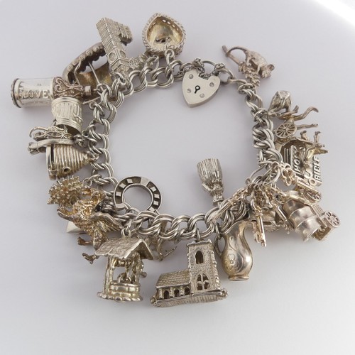 322 - A silver Charm Bracelet, with twenty five silver and white metal charms suspended, mostly unmarked, ... 