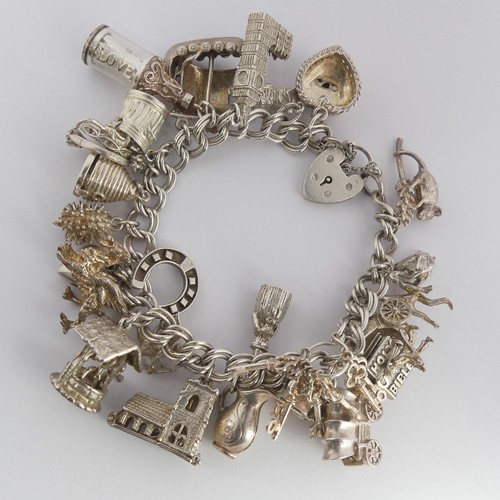 322 - A silver Charm Bracelet, with twenty five silver and white metal charms suspended, mostly unmarked, ... 