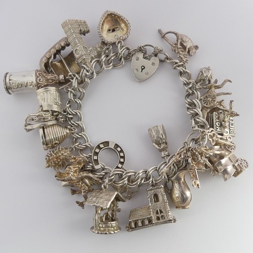 322 - A silver Charm Bracelet, with twenty five silver and white metal charms suspended, mostly unmarked, ... 