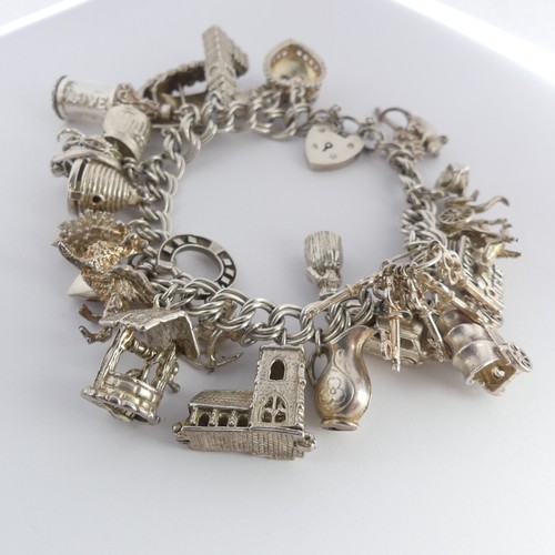 322 - A silver Charm Bracelet, with twenty five silver and white metal charms suspended, mostly unmarked, ... 