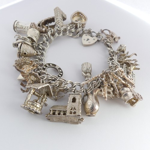 322 - A silver Charm Bracelet, with twenty five silver and white metal charms suspended, mostly unmarked, ... 