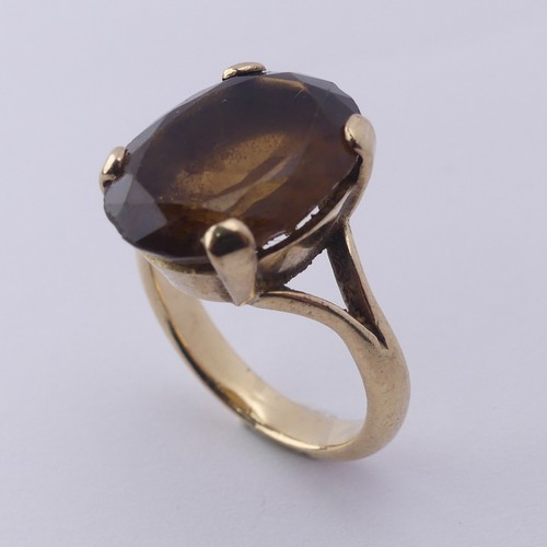 256 - A smoky quartz Dress Ring, the oval facetted stone 16mm long, four claw set in unmarked gold, tested... 