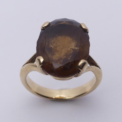 256 - A smoky quartz Dress Ring, the oval facetted stone 16mm long, four claw set in unmarked gold, tested... 