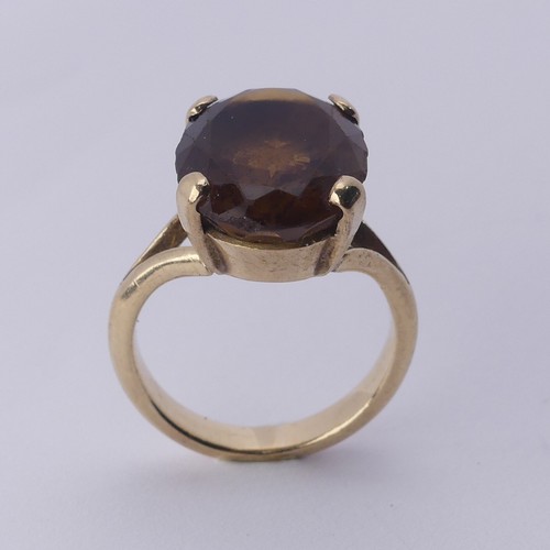 256 - A smoky quartz Dress Ring, the oval facetted stone 16mm long, four claw set in unmarked gold, tested... 