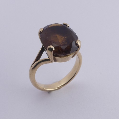 256 - A smoky quartz Dress Ring, the oval facetted stone 16mm long, four claw set in unmarked gold, tested... 