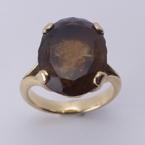 256 - A smoky quartz Dress Ring, the oval facetted stone 16mm long, four claw set in unmarked gold, tested... 