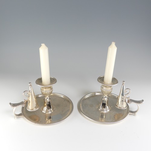 A pair of George III silver Chamber Sticks, by William Stroud, hallmarked London, 1807, the bases, snuffers and drip trays all correspondingly marked, of plain circular form with gadrooned rim and leaf capped handle, engraved crest and monogram fading, 15cm diameter, approx. total weight 30ozt (2)