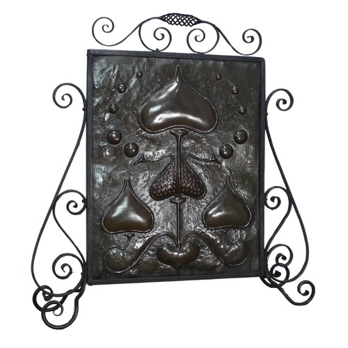 645 - An Art Nouveau copper Firescreen, embossed with stylised hearts and foliage, framed in scrolled wrou... 