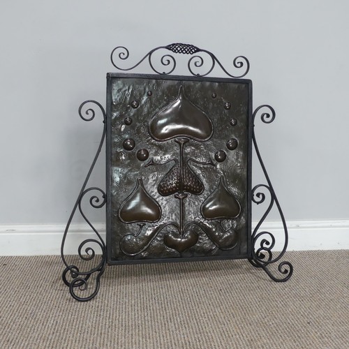 645 - An Art Nouveau copper Firescreen, embossed with stylised hearts and foliage, framed in scrolled wrou... 