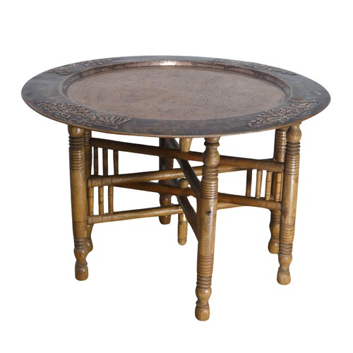 626 - A large Arts and Crafts copper tray Table, outer rim embossed with stylised flowers, with folding st... 