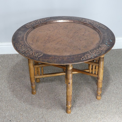 626 - A large Arts and Crafts copper tray Table, outer rim embossed with stylised flowers, with folding st... 