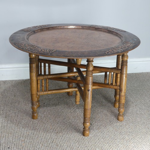 626 - A large Arts and Crafts copper tray Table, outer rim embossed with stylised flowers, with folding st... 